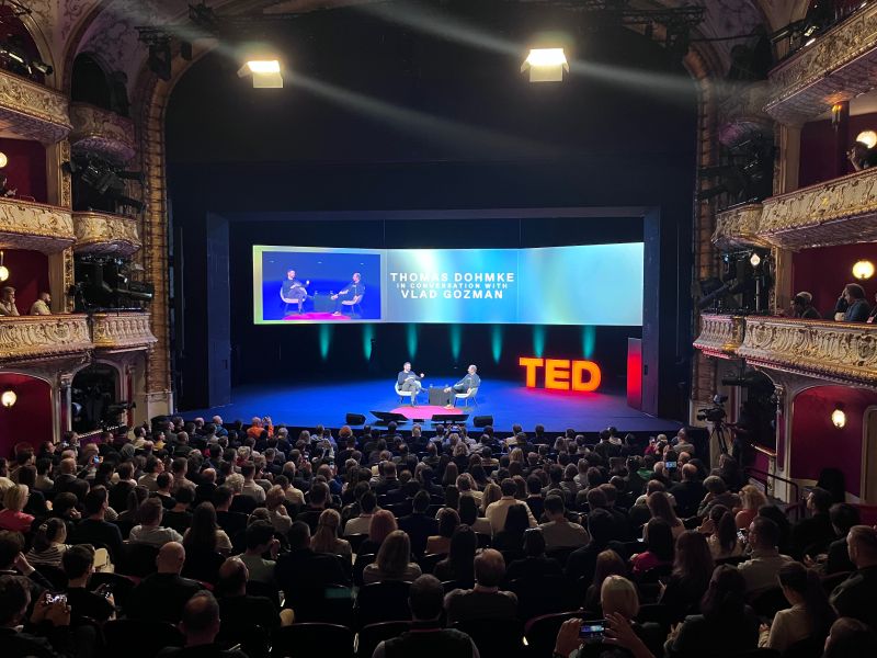 TED AI conference in Vienna. A large audience attentively watching a TED Talk presentation on stage, with a speaker engaging the crowd.